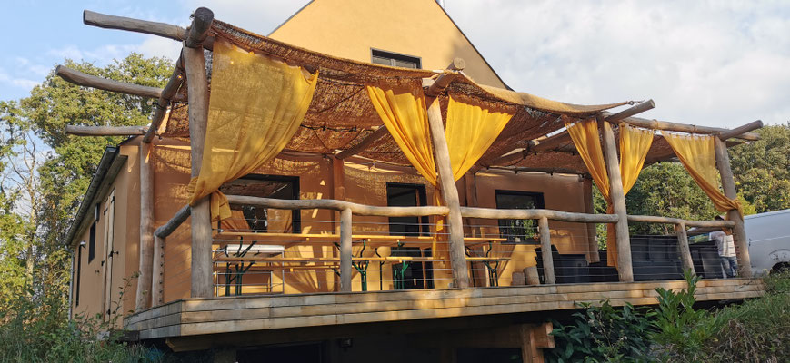 Terrasse sur pilotis avec pergola en bois flotté et voilages